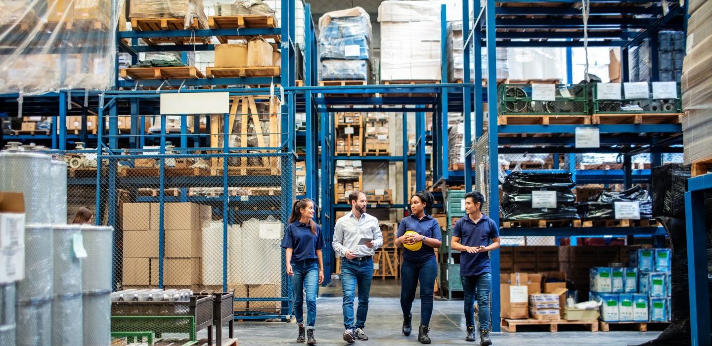Warehouse employees walking through aisle and talking Produktionshalle